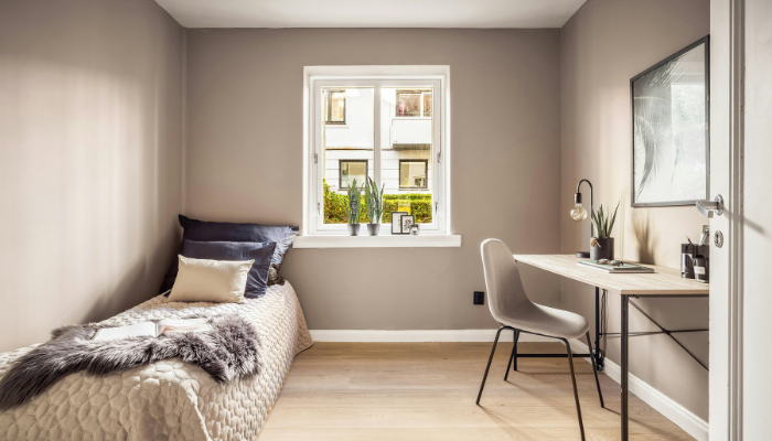 A single bed  and desk with a window in the middle